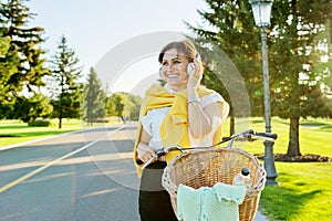 Beautiful active mature woman with bike on the road in the park