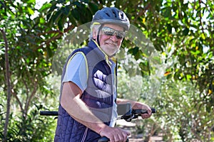 Beautiful active senior man with electro bikes standing outdoors in the park. Happy elderly grandfather running in nature with his