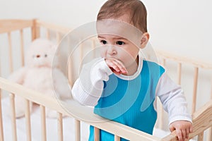 Beautiful adorable baby toddler look at one side in the bed with a bear on white background
