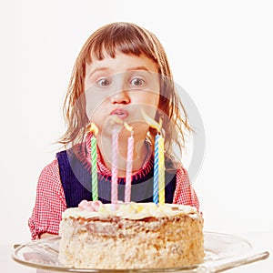 Beautiful adorable child girl blowing out the candle on her birthday cake. Holiday, happy childhood and birthday concept