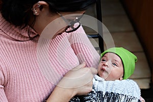 Beautiful and adorable newborn baby with a green hat, held by his mother while he sleeps and caressed by both parents