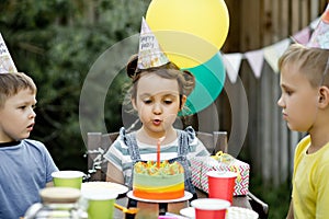 Beautiful adorable six year old girl celebrating her birthday with family or friends, blowing candles on homemade baked