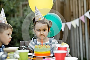 Beautiful adorable six year old girl celebrating her birthday with family or friends, blowing candles on homemade baked