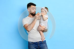 Beautiful adorable todler using a bottle while sitting in her father`s arms