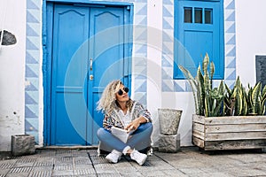 Beautiful adult blonde curly model woman sit down on the floor with paper book enjoying her alternative lifestyle - travel and