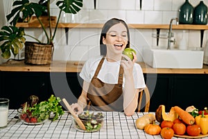 beautiful adult woman with bell peppers looking at camera while making salad at kitche. healthy food concept photo