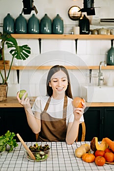 beautiful adult woman with bell peppers looking at camera while making salad at kitche. healthy food concept photo