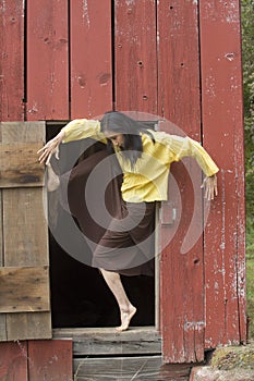 Beautiful adult woman dancer in open door of red barn