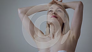 Beautiful adult woman with naked shoulders touches her face.