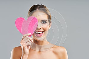 Beautiful adult woman posing over gray background with heart