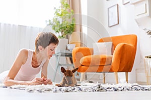 Beautiful adult woman practicing yoga pose with pygmy pinscher dog enjoying