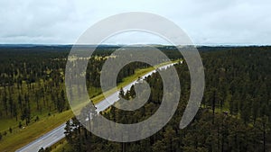 Beautiful aerial background shot of national forest in USA with lush green trees and delivery truck moving along highway