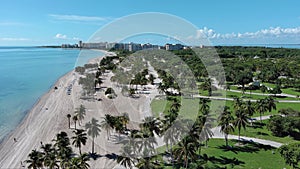 beautiful aerial footage along the coast of the Atlantic ocean with green palm trees and grass, a sandy beach and hotel