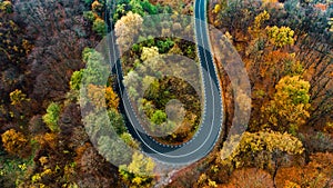 Beautiful aerial landscape of mountain forest road. Aerial view of curvy road in beautiful autumn forest. Top view of roadway with