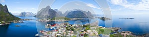 Beautiful aerial panorama of the blue sea surrounding the fishing village and rocky peaks Reine, Moskenes, Lofoten, Norway, sunny