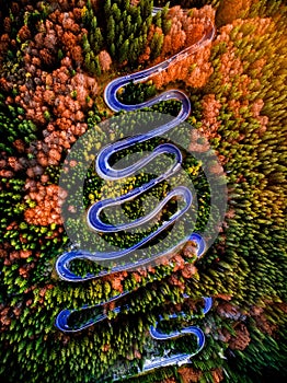 Beautiful aerial view of a curvy winding road with serpentine and colorful autumn trees