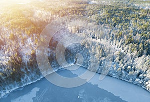 Beautiful aerial view from drone of winter landscape with forest, snow, frozen lake and river. Rime ice and hoar frost covering tr