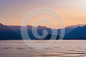 Beautiful aerial view of the famous Como Lake on purple sunset. Clouds reflecting in calm waters of the lake with Alp mountain