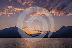 Beautiful aerial view of the famous Como Lake on purple sunset. Clouds reflecting in calm waters of the lake with Alp mountain