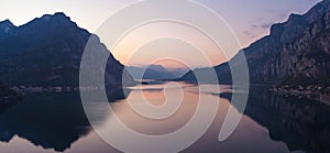 Beautiful aerial view of the famous Como Lake on purple sunset. Mountains reflecting in calm waters of the lake with Alp mountain