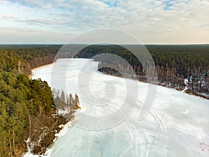 Beautiful aerial view of ice covered Balzis lake. Snowy pine forests surrounding a small lake. Scenic winter landscape near