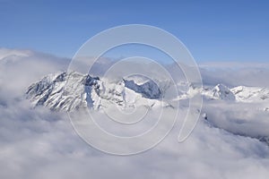 Beautiful aerial view of snow capped mountain peaks above clouds