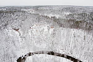 Beautiful aerial view of snow covered pine forests and a river winding among trees. Rime ice and hoar frost covering trees