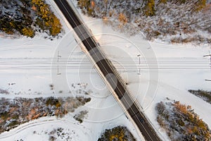 Beautiful aerial view of snow covered pine forests and a road winding among trees. Rime ice and hoar frost covering trees