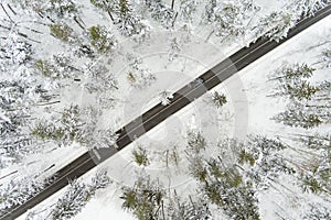 Beautiful aerial view of snow covered pine forests and a road winding among trees. Rime ice and hoar frost covering trees
