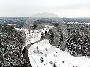 Beautiful aerial view of snow covered pine forests and a road winding among trees. Rime ice and hoar frost covering trees. Scenic