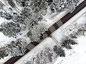 Beautiful aerial view of snow covered pine forests and a road winding among trees. Rime ice and hoar frost covering trees. Scenic