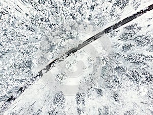 Beautiful aerial view of snow covered pine forests and a road winding among trees. Rime ice and hoar frost covering trees. Scenic