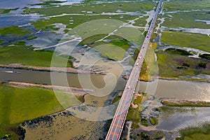 Beautiful aerial view of traffic on elevated road and tollway surrounded green rice fields