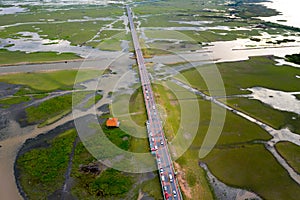 Beautiful aerial view of traffic on elevated road and tollway surrounded green rice fields