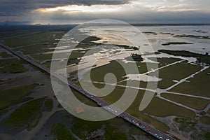 Beautiful aerial view of traffic on elevated road and tollway surrounded green rice fields