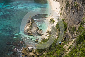 Beautiful aerial view of tropical paradise beach and rock cliff with amazing turquoise sea water and palm trees in Summer holidays