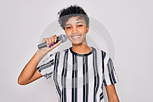 Beautiful african american afro singer woman singing using microphone over white background with a happy face standing and smiling