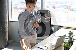 Beautiful african american business woman in smart casual wear working on laptop in the office