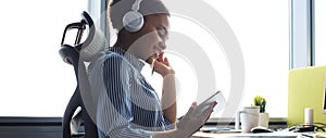 Beautiful african american business woman is working using digital tablet while sitting in creative office