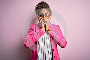 Beautiful african american businesswoman wearing jacket and glasses over pink background afraid and shocked, surprise and amazed