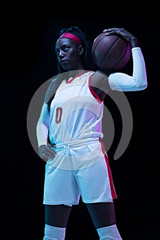 Beautiful african-american female basketball player in motion and action in neon light on black background. Concept of