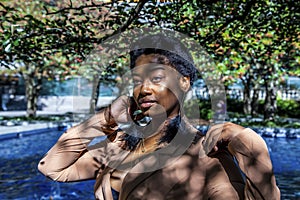 African american  female fashion model with an Afro is sitting in a park by in Chicago.