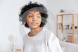 Beautiful african american girl with afro hairstyle at home indoor. Young african woman with curly hair in living room