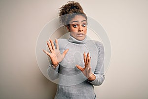 Beautiful african american girl wearing turtleneck sweater standing over white background afraid and terrified with fear