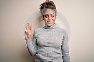 Beautiful african american girl wearing turtleneck sweater standing over white background showing and pointing up with fingers