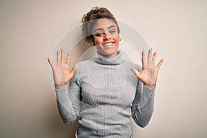 Beautiful african american girl wearing turtleneck sweater standing over white background showing and pointing up with fingers