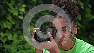 Beautiful African American mixed race biracial teenager young woman using a digital camera outside
