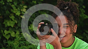 Beautiful African American mixed race biracial teenager young woman using a digital camera outside