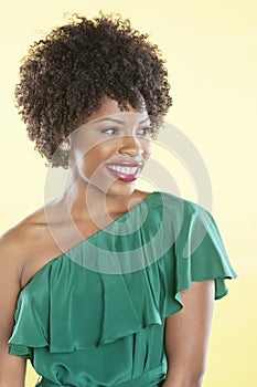 Beautiful African American in an off shoulder dress looking away over colored background