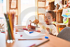 Beautiful african american toddler playing with dinosaurs toy on desk at kindergarten